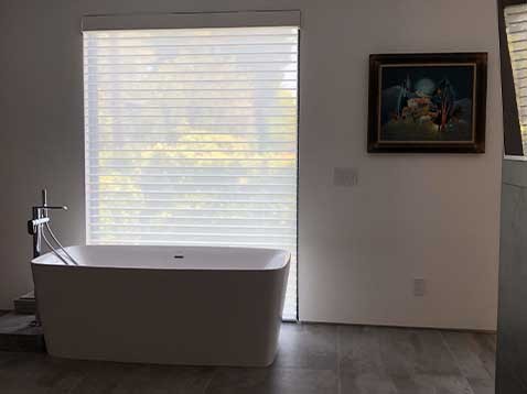 Bathtub next to a tall window